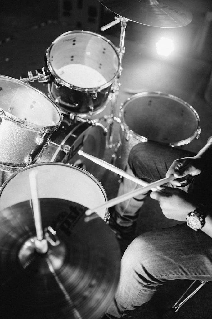 A musician playing a drum kit in a black and white photo. Captures the energy and focus of the performance.